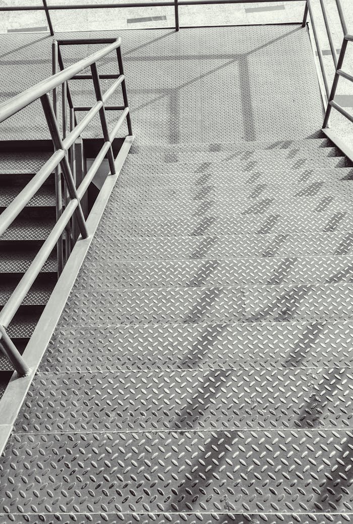 Top view of a modern industrial staircase with metal steps and railings, showcasing geometric patterns.