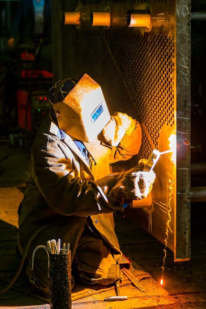 A skilled welder works with a torch in an industrial environment, showcasing metalwork expertise.